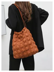 Detail van de bruine gewatteerde tote bag met bubbeltextuur en dunne lederen riem