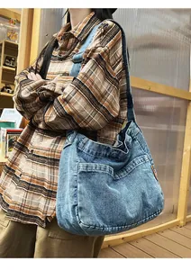 Detail of blue denim shoulder bag with double front pockets and metal chain accessory