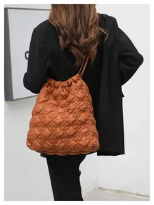 Detailopname van de karamel gewatteerde bucket bag met textuur en trekkoordsluiting