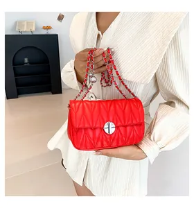 Gros plan du sac matelassé rouge avec fermoir argenté et détail de bandoulière chaîne