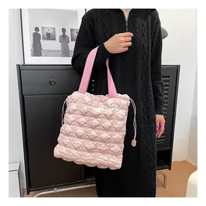 Close-up of pink quilted tote bag with side drawstring detail and rhombus patterns