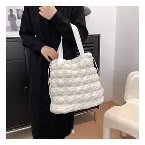 Close-up of quilted bubble texture and side drawstring on white puffy tote bag