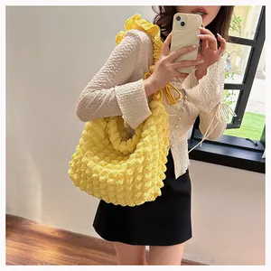 Detail of a bright yellow pleated bubble tote bag with decorative ruffled shoulder strap