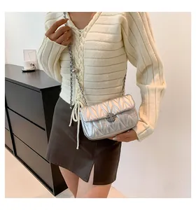Détail du sac bandoulière argenté matelassé avec chaîne en métal et sphère décorative