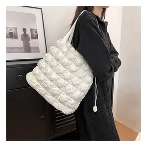 Close-up of white puffer quilted tote bag with bubble texture shown on shoulder