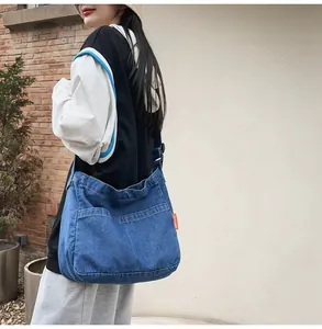 Macro view of blue denim crossbody bag featuring contrast stitching and orange label tag