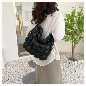 Detailed view of black puffy quilted fabric texture and pleated surface on a shoulder bag