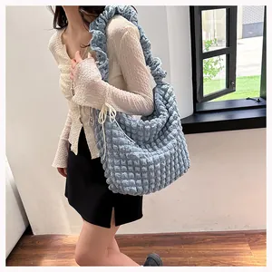 Detail of light blue popcorn textured shoulder bag with stylish ruffle strap design