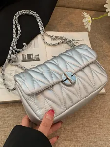 Sac argenté chic matelassé avec surpiqûres en V et fermoir rotatif circulaire