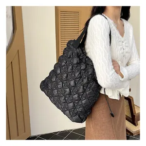 Detail of black quilted shoulder bag with bubble texture shown on a female model