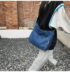 Detail of vintage blue denim crossbody bag with side orange label and twin front pockets