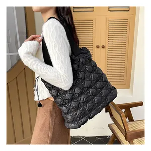 Quilted black bubble tote bag featuring adjustable drawstring side details and wide strap