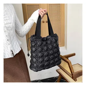 Close-up of black quilted puffer tote bag with diamond stitching and woven handles
