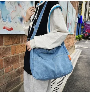 Street view of blue denim crossbody bag with multiple pockets and wide strap