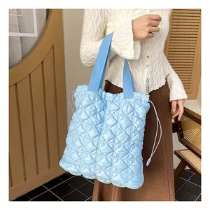 Detail of light blue quilted tote bag with drawstring closure and woven strap