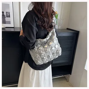 Silver metallic quilted puff tote bag with ruched texture shown on shoulder of a model