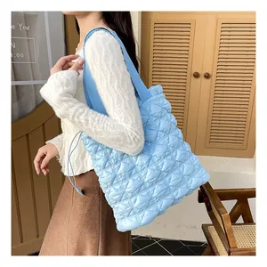 Detail of light blue quilted tote bag showing rhombus texture and woven shoulder strap