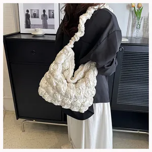 Lifestyle shot of white pleated cloud tote bag with puff texture on a model's shoulder