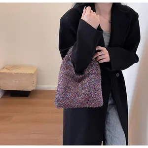 Detail of colorful plush woven underarm bag with shimmering metallic threads on model