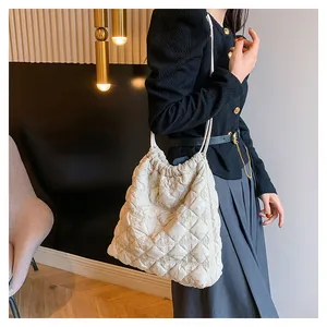 Detailweergave van witte gewatteerde dons nylon draagtas met zachte wolkentextuur en riemen