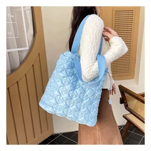 Close-up of quilted light blue bubble tote bag with padded texture and drawstring detail
