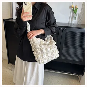 Lifestyle shot of white puff tote bag with quilted texture worn by model with black shirt