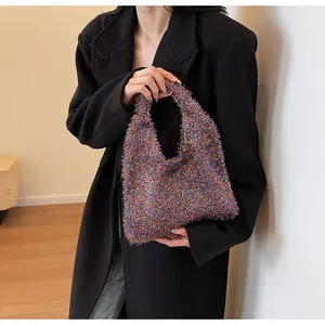 Detail of colorful tassel handbag with metallic texture held against a black blazer