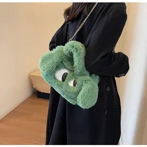Dettaglio della borsa in peluche verde con grandi occhi carini e trama soffice al tatto