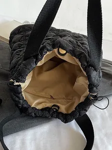 Quilted puffer tote bag in black featuring spacious interior and zipper pocket