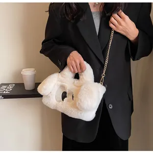 Dettaglio della borsa in peluche bianca con occhi a cartone e catena d'oro sulla modella