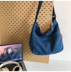 Detail view of a vintage dark blue denim hobo bag with front pocket and orange side label