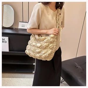 Detail of golden quilted puffy tote bag featuring pleated strap and satin finish