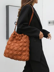Gewatteerde caramel bucket bag met schouderband gedragen door een model in de stad