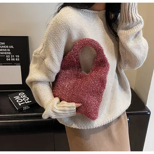 Detailed texture of dark pink glitter mini hobo bag held against a white sweater