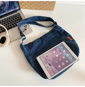 Blue denim messenger bag detail showing spacious interior capacity with an iPad inside