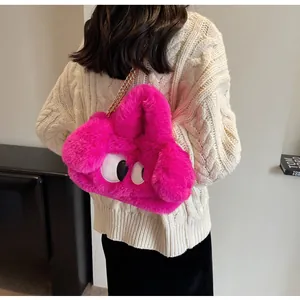 Dettaglio borsa di peluche rosa con occhi a cartone e tracolla a catena d'oro