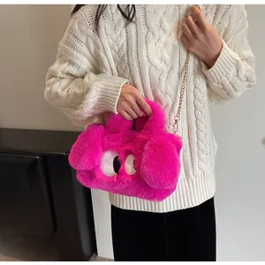 Dettaglio della borsa in peluche rosa con occhi a cartone e tracolla a catena d'oro