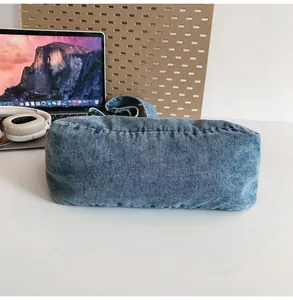Detail view of denim crossbody bag showing fabric texture and neat stitching on the bottom