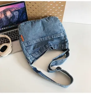 Macro detail of blue denim shoulder bag featuring a signature orange side label