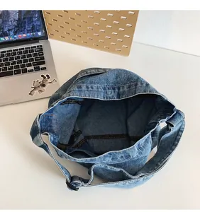 Detail view of denim crossbody bag showing fabric texture and spacious interior compartment