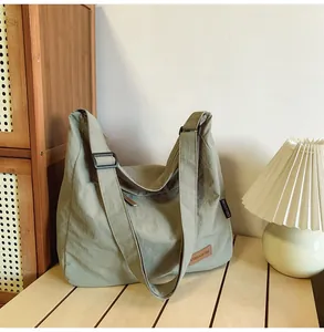 Detail of green canvas tote showing brown leather logo patch and water-resistant fabric