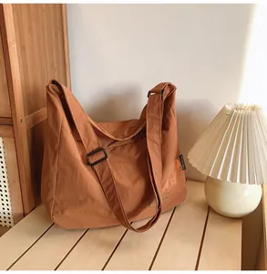 Detail of caramel canvas shoulder bag showing adjustable strap and brand label