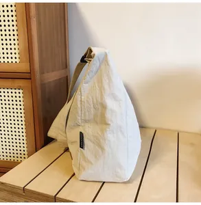 Close-up of textured canvas bag showing detailed CHUANGMI brand tag and fabric pleats