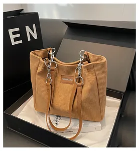 Detalle de un bolso tote de pana marrón con cadena dentro de una caja de regalo