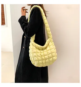 Detailopname van een gewatteerde gele puffy hobo-tas van glanzende nylon voor dames