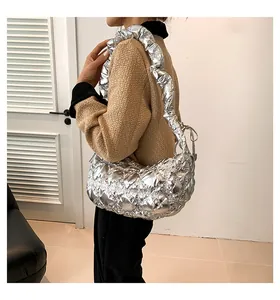 Silberne Metallic-Wolkentasche mit Faltenstruktur und Steppmuster am weiblichen Model