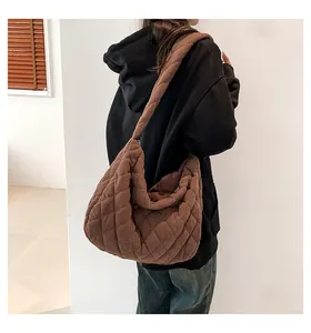 Detail einer braunen gesteppten Cord-Hobo-Tasche mit Fokus auf Textur und Design am Modell