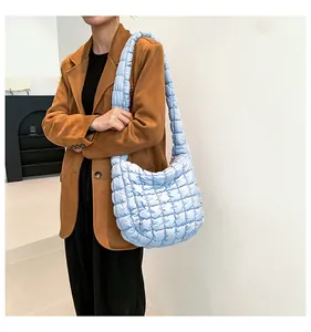 Lichtblauwe gewatteerde cloud bag gedragen door model met een bruine blazer jas