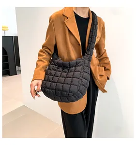 Detail van zwarte gewatteerde crossbodytas met grote ruitstiksels en gevoerde schouderriem