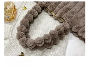 Détail de l'anse d'un sac cabas en peluche marron avec pompons et surpiqûres verticales
